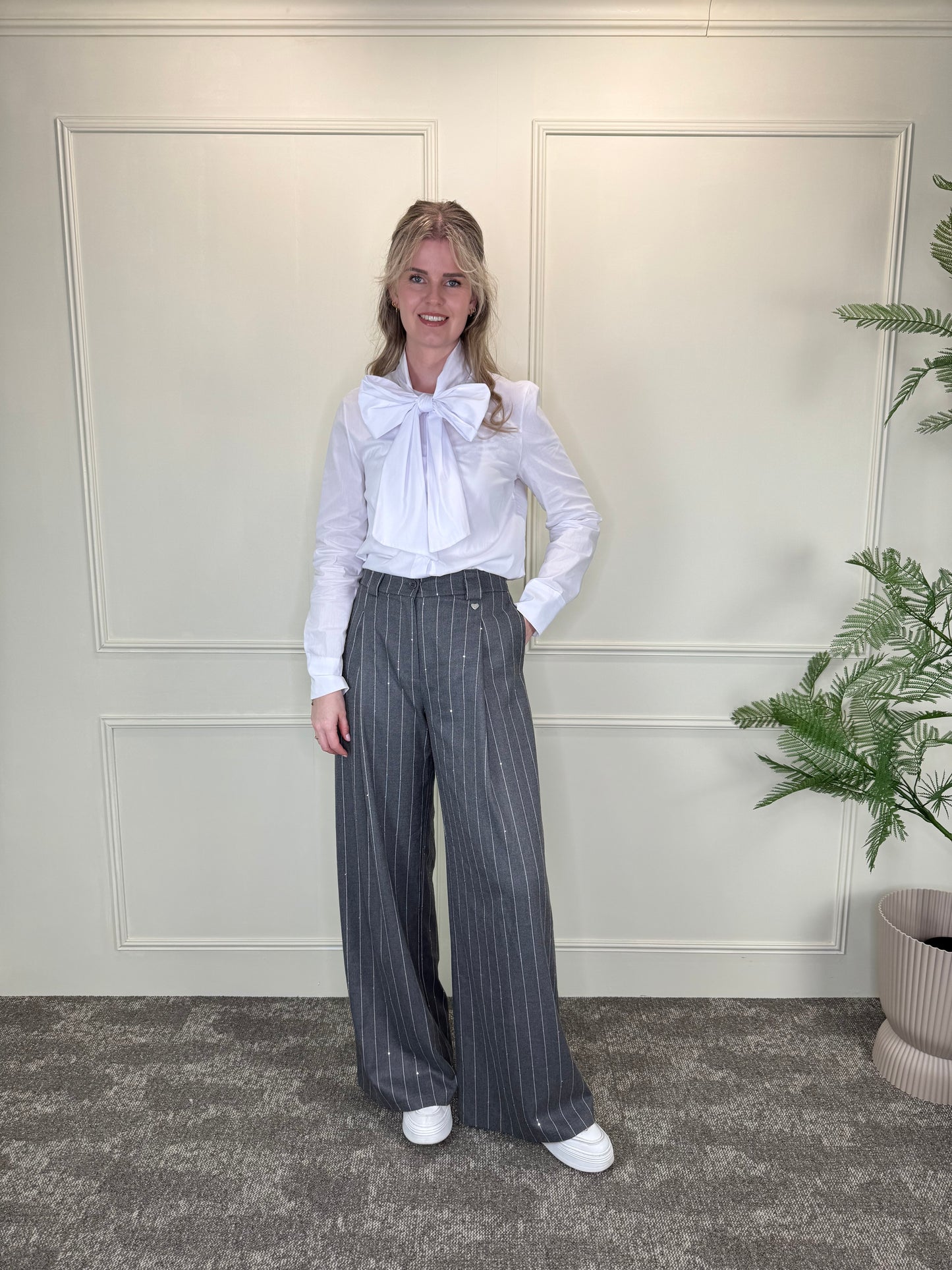 Grijze pantalon met krijtstreep en pailletten, gecombineerd met witte blouse met strikdetail Label Rozay