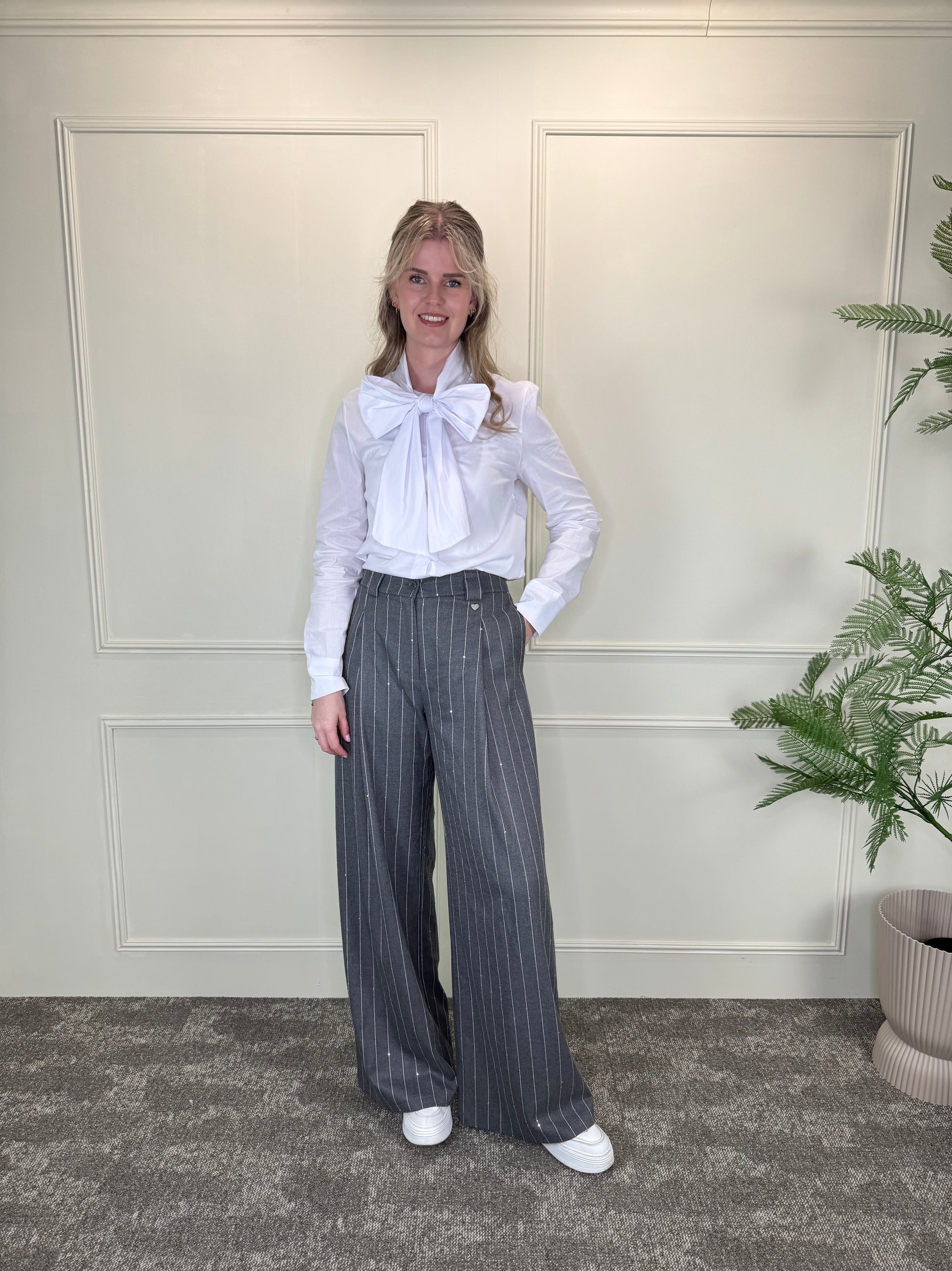 Grijze pantalon met krijtstreep en pailletten, gecombineerd met witte blouse met strikdetail Label Rozay