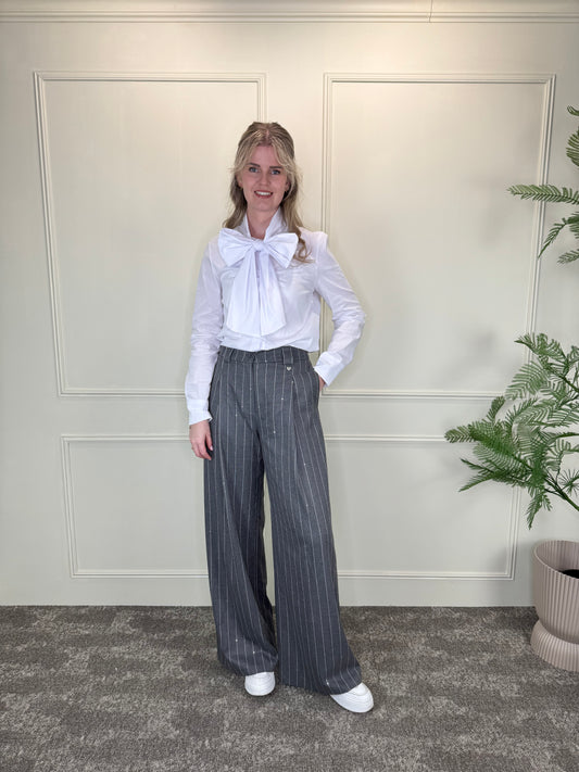 Grijze pantalon met krijtstreep en pailletten, gecombineerd met witte blouse met strikdetail Label Rozay